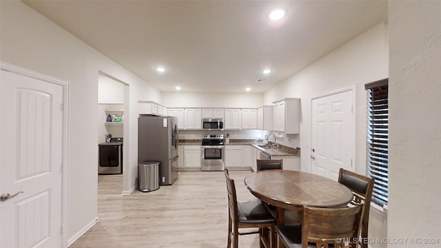 dining area featuring washer / clothes dryer, light hardwood / wood-style flooring, and sink