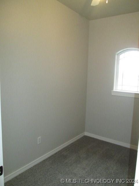 empty room with dark carpet and ceiling fan