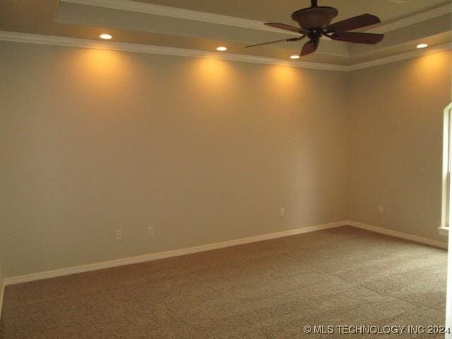 empty room with carpet, a tray ceiling, ceiling fan, and crown molding