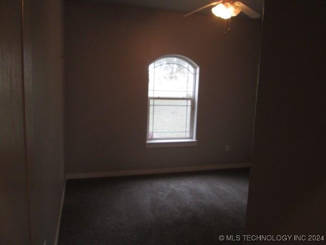 unfurnished room featuring dark colored carpet and ceiling fan