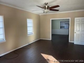 empty room with ceiling fan, dark hardwood / wood-style floors, and ornamental molding