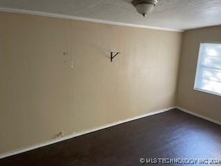 unfurnished room featuring dark wood-type flooring and ornamental molding