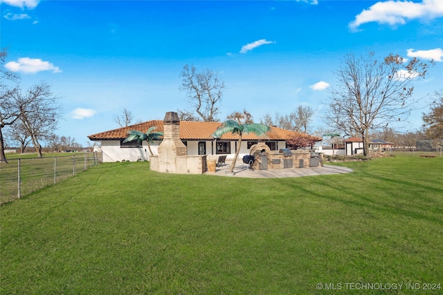 rear view of property featuring a yard, a patio area, and exterior kitchen