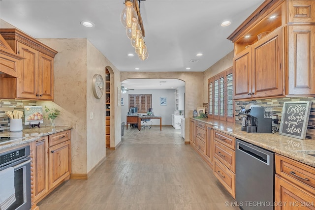 kitchen featuring light stone counters, ceiling fan, stainless steel appliances, and decorative light fixtures