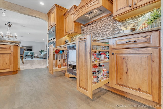 kitchen with decorative backsplash, stainless steel oven, custom range hood, pendant lighting, and a notable chandelier