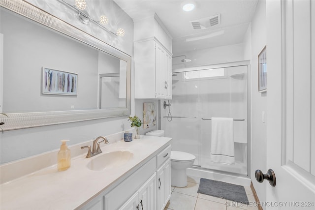 bathroom featuring toilet, vanity, tile patterned floors, and a shower with shower door