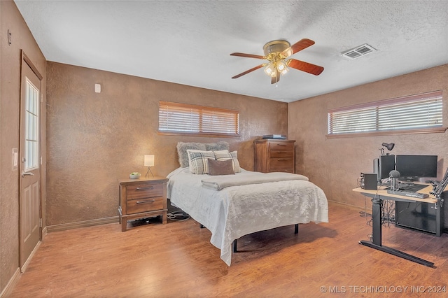 bedroom with hardwood / wood-style flooring, ceiling fan, and multiple windows