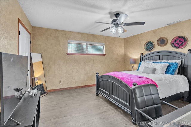 bedroom featuring ceiling fan, light hardwood / wood-style floors, and a textured ceiling