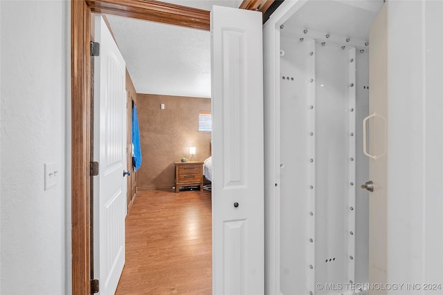 hallway with a textured ceiling and light hardwood / wood-style flooring