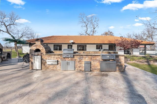 view of patio / terrace featuring an outdoor kitchen and a grill