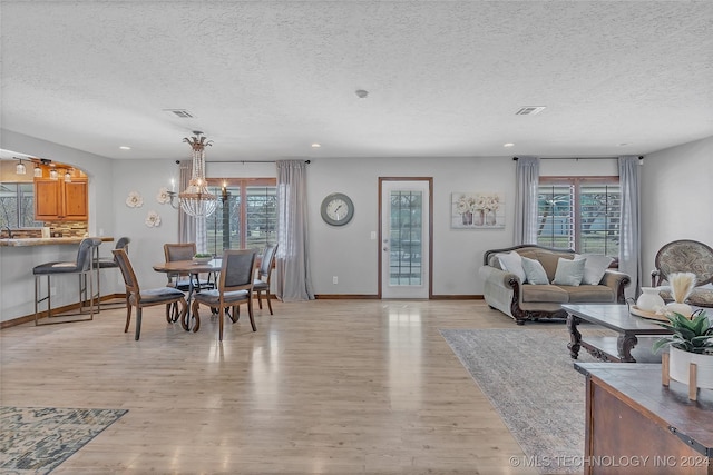 living room with a textured ceiling, light wood-type flooring, and plenty of natural light