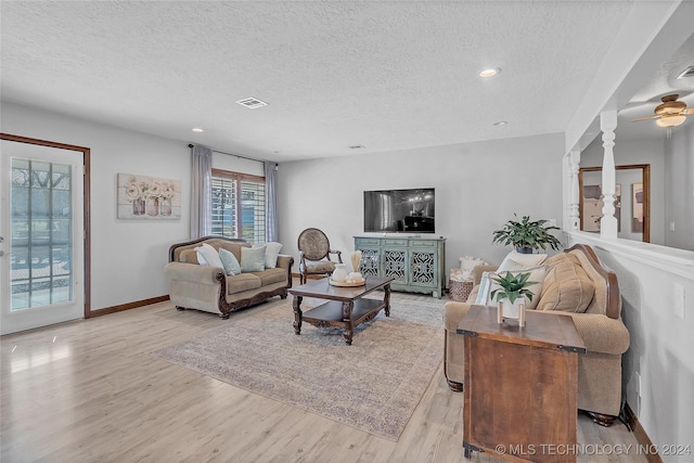 living room with a textured ceiling, light hardwood / wood-style flooring, and ceiling fan