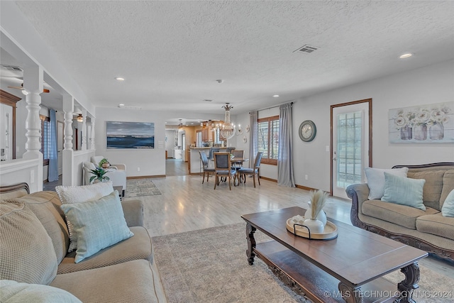 living room featuring a chandelier, a textured ceiling, and light wood-type flooring