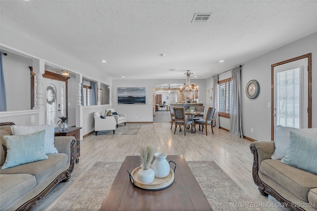 living room featuring a chandelier, a textured ceiling, and light hardwood / wood-style flooring