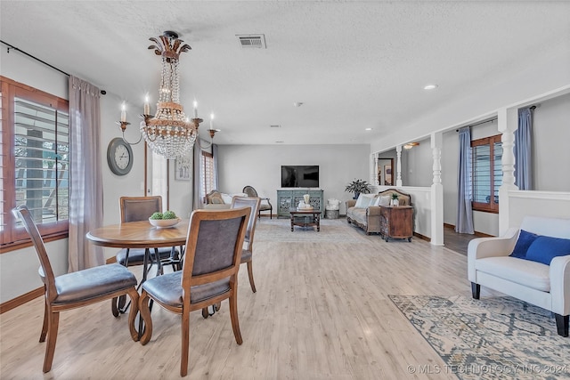 dining room featuring a textured ceiling, light hardwood / wood-style floors, and a notable chandelier