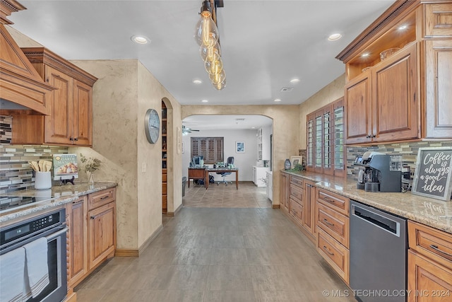 kitchen featuring light stone countertops, decorative light fixtures, stainless steel appliances, and ceiling fan