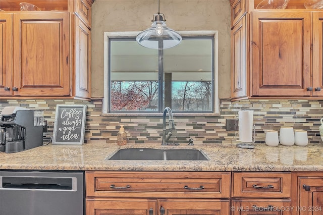 kitchen featuring tasteful backsplash, light stone counters, sink, decorative light fixtures, and dishwasher