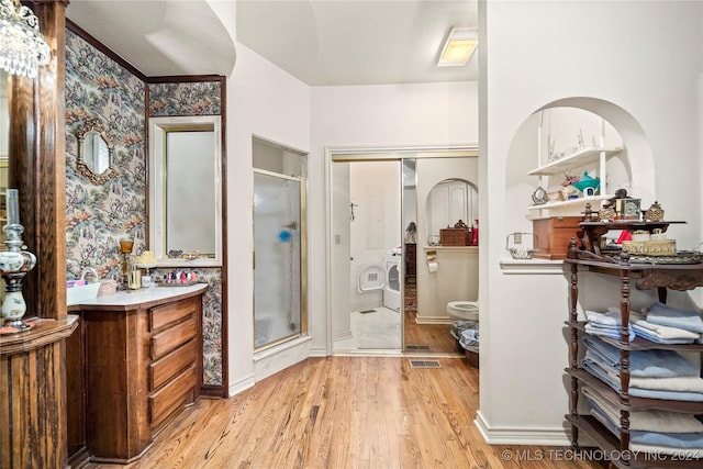 bathroom with hardwood / wood-style floors, vanity, washing machine and dryer, and walk in shower