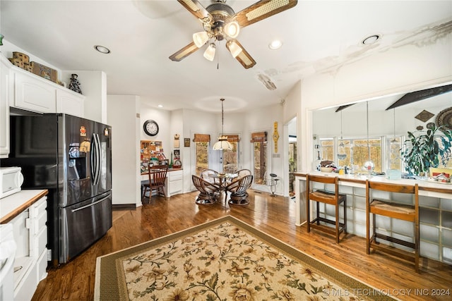 kitchen featuring ceiling fan, dark wood-type flooring, stainless steel fridge, decorative light fixtures, and white cabinets