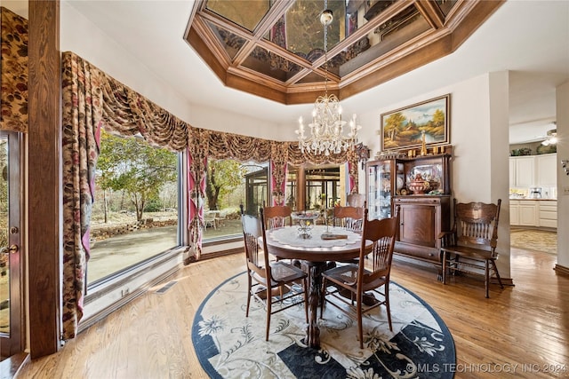 dining area with coffered ceiling, ceiling fan with notable chandelier, crown molding, and light hardwood / wood-style flooring