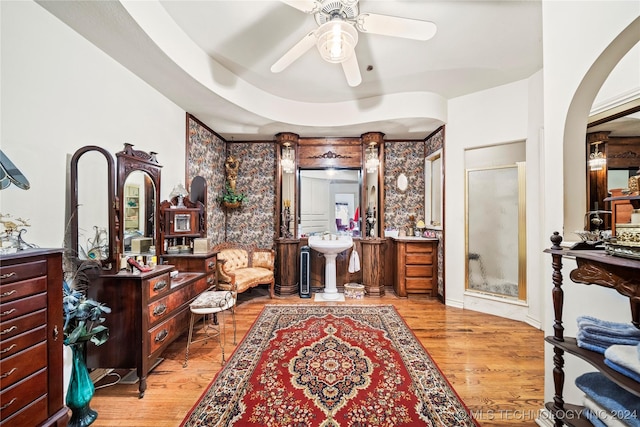 interior space with a tray ceiling, ceiling fan, a shower with shower door, and hardwood / wood-style flooring