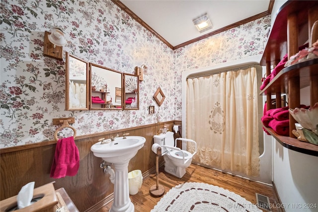 bathroom featuring wood walls, wood-type flooring, and ornamental molding