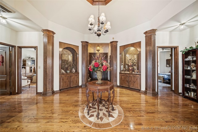 entrance foyer featuring ornate columns, a chandelier, and hardwood / wood-style flooring