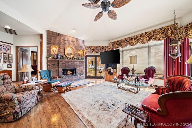 living room featuring ceiling fan, a healthy amount of sunlight, wood-type flooring, and a fireplace