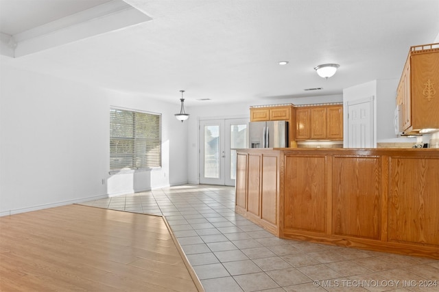 kitchen with kitchen peninsula, stainless steel fridge, light hardwood / wood-style floors, and hanging light fixtures