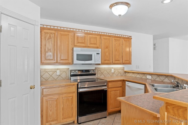 kitchen featuring tasteful backsplash, sink, light tile patterned floors, and white appliances