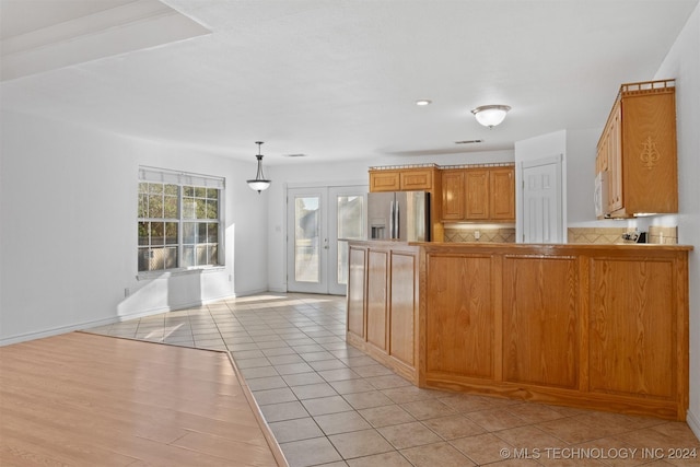 kitchen with pendant lighting, backsplash, stainless steel fridge with ice dispenser, light tile patterned floors, and kitchen peninsula