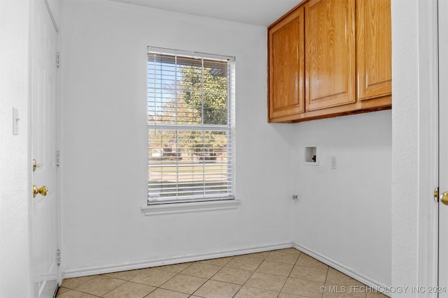 clothes washing area featuring cabinets, light tile patterned floors, and hookup for a washing machine