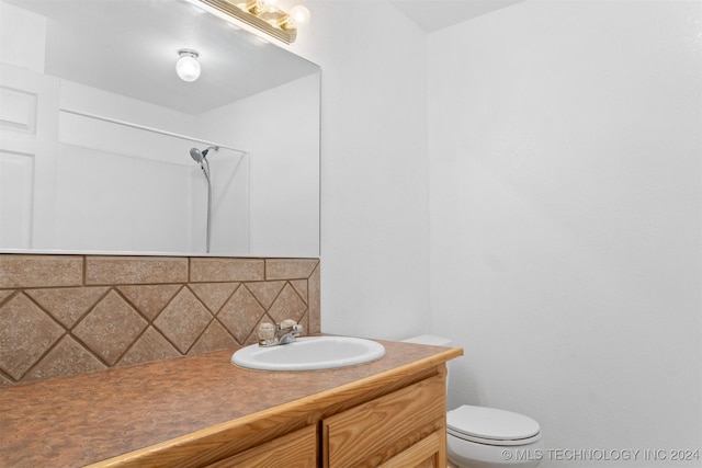 bathroom featuring vanity, backsplash, toilet, and walk in shower