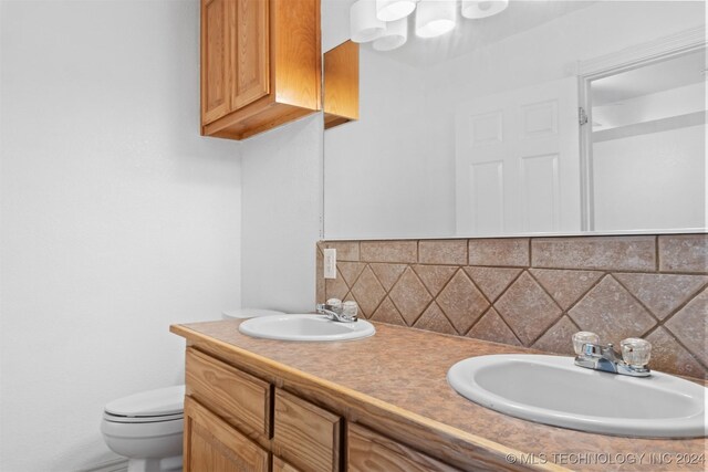 bathroom featuring decorative backsplash, toilet, and vanity