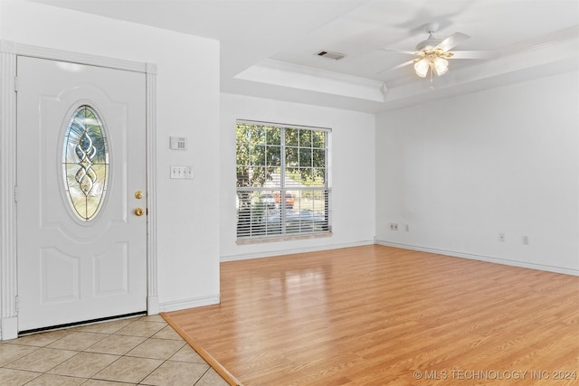 entryway with light hardwood / wood-style floors, a raised ceiling, ceiling fan, and a healthy amount of sunlight