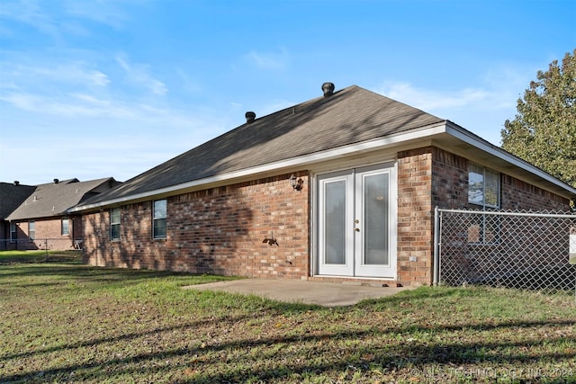 rear view of property featuring a lawn, a patio, and french doors