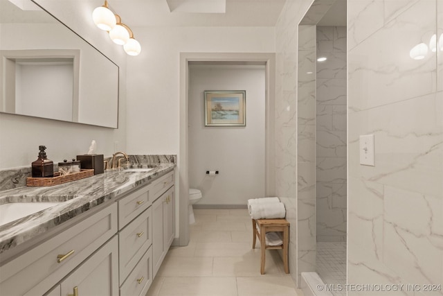 bathroom with tile patterned flooring, vanity, toilet, and tiled shower