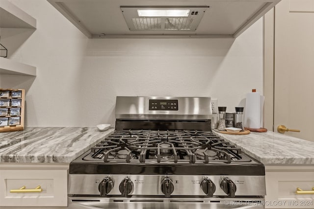 kitchen with light stone counters, white cabinetry, and stainless steel range with gas stovetop