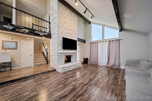 unfurnished living room with beamed ceiling, hardwood / wood-style flooring, high vaulted ceiling, and a stone fireplace