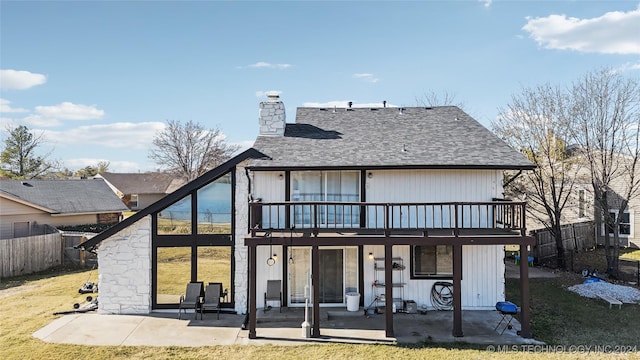 rear view of property with a yard, a balcony, and a patio