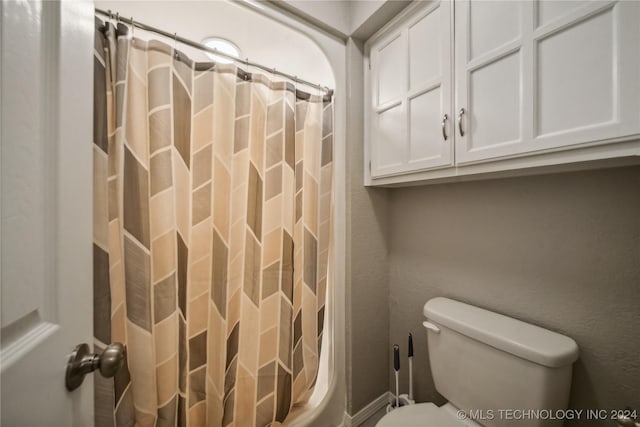 bathroom featuring a shower with shower curtain and toilet