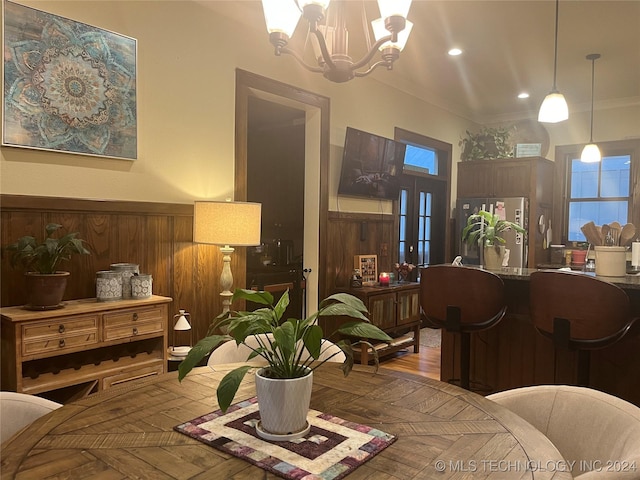 interior space with wooden walls, ornamental molding, and a chandelier