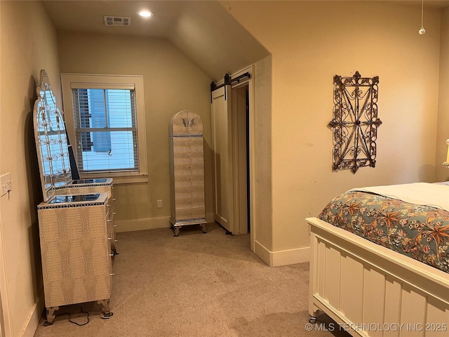 bedroom with a barn door, lofted ceiling, and light carpet