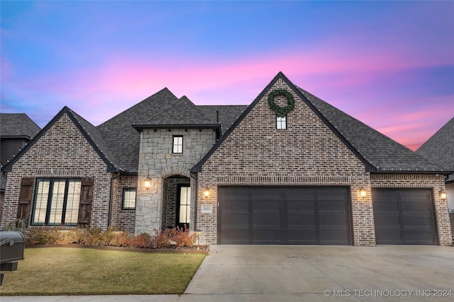 french country style house with a yard and a garage