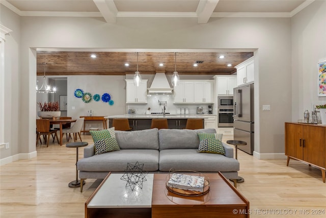 living room featuring beam ceiling, crown molding, a chandelier, and light wood-type flooring