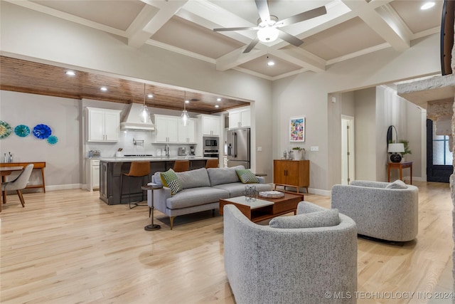 living room with beam ceiling, ceiling fan, coffered ceiling, and light wood-type flooring