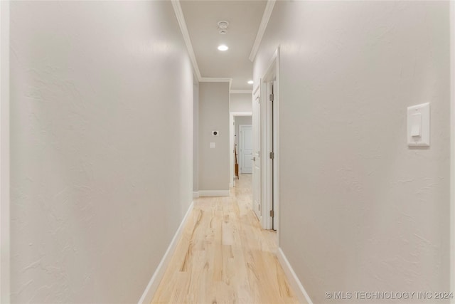 hallway featuring crown molding and light hardwood / wood-style flooring