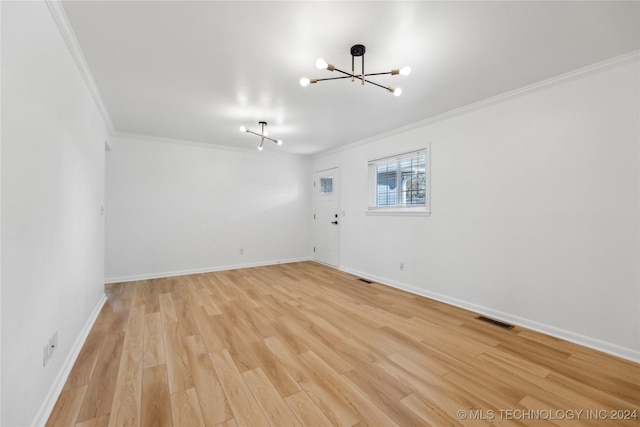 spare room featuring a chandelier, crown molding, and light hardwood / wood-style floors