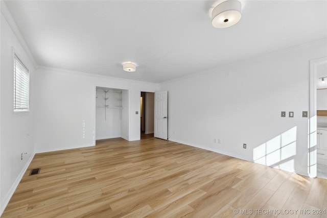 unfurnished bedroom featuring a closet, ornamental molding, and light hardwood / wood-style flooring