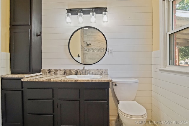 bathroom featuring vanity, toilet, a wealth of natural light, and wood walls